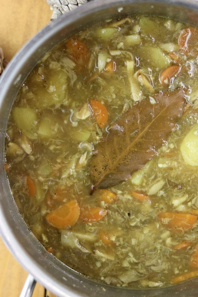 Almost cooked soup with a bay leaf floating at the top.